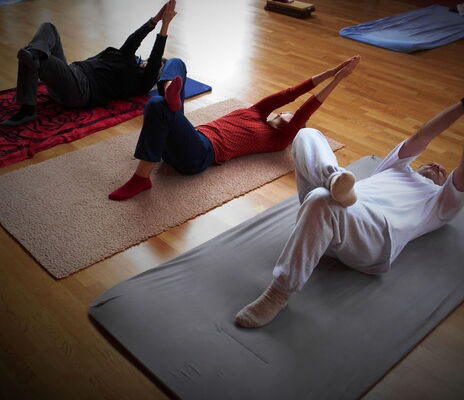 Drei Personen liegen auf Matten und machen eine Feldenkrais-Übung.